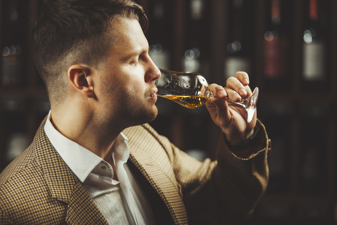 Caucasian sommelier tasting whiskey taste on the cellar background.
